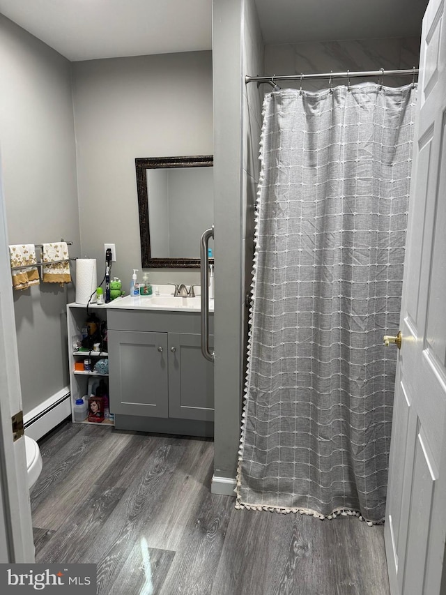 full bath featuring a baseboard heating unit, a shower with curtain, vanity, and wood finished floors