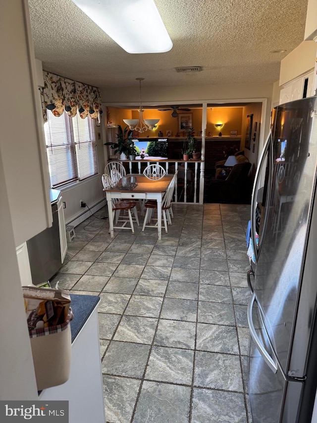 dining area featuring a baseboard heating unit, stone finish flooring, visible vents, and a textured ceiling