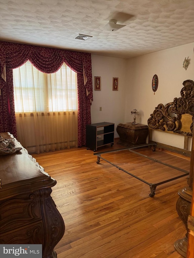 bedroom featuring visible vents, light wood-style flooring, and a textured ceiling