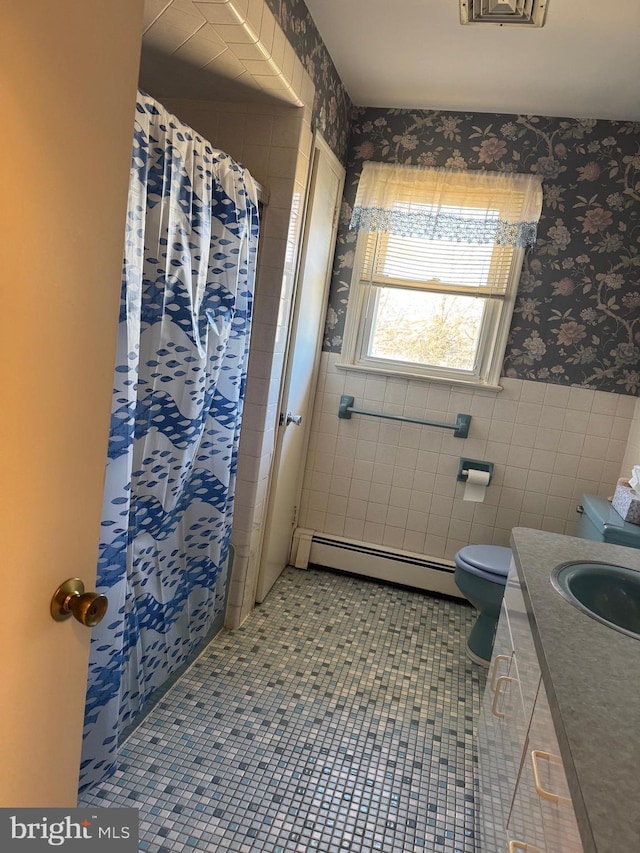 full bath with wallpapered walls, toilet, a wainscoted wall, a baseboard radiator, and tile walls