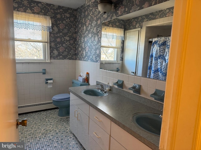 bathroom featuring a baseboard heating unit, wainscoting, a sink, and wallpapered walls