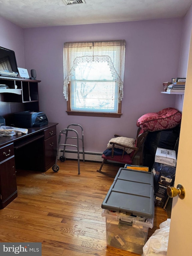 home office featuring a baseboard heating unit, wood finished floors, and visible vents