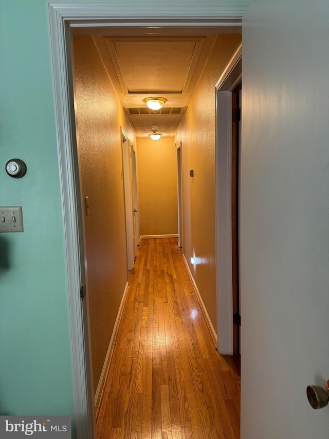 corridor with light wood finished floors and baseboards