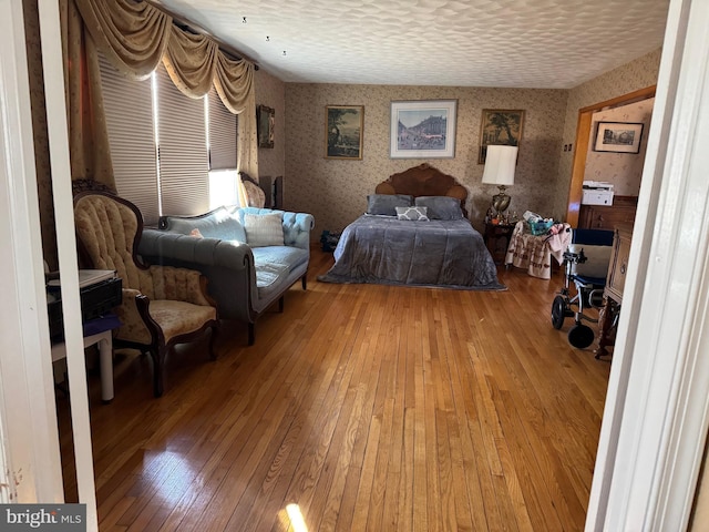 bedroom featuring a textured ceiling, light wood-style flooring, and wallpapered walls