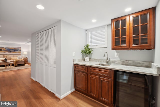 bar with beverage cooler, a sink, light wood-style flooring, and recessed lighting