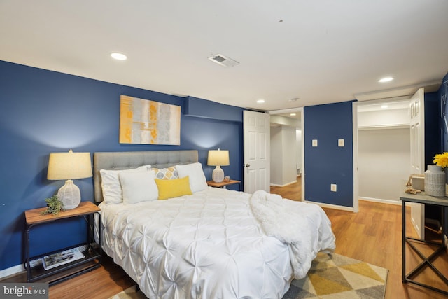 bedroom with recessed lighting, visible vents, baseboards, and wood finished floors