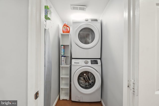 washroom featuring visible vents, stacked washer / dryer, wood finished floors, laundry area, and baseboards