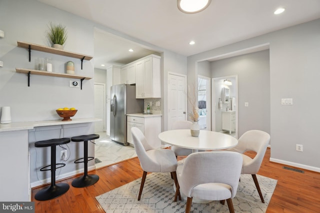 dining room featuring light wood finished floors, baseboards, visible vents, and recessed lighting