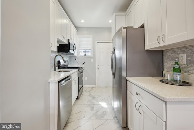 kitchen featuring marble finish floor, white cabinetry, appliances with stainless steel finishes, and decorative backsplash