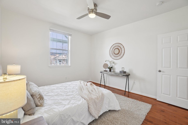 bedroom with ceiling fan, wood finished floors, and baseboards