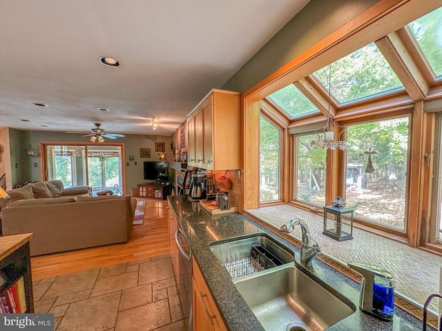 kitchen with dishwashing machine, open floor plan, stone tile flooring, a sink, and recessed lighting