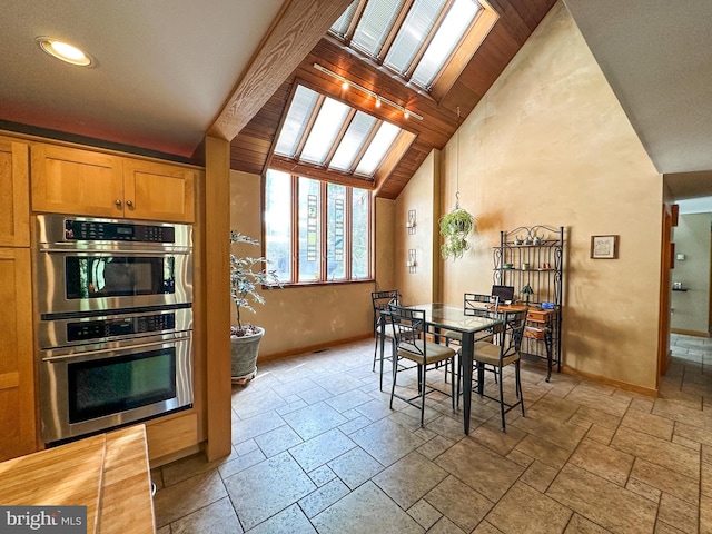 dining area featuring high vaulted ceiling, baseboards, and stone tile floors