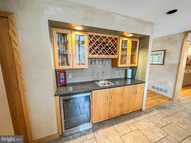 bar featuring wine cooler, stone tile floors, visible vents, a sink, and wet bar