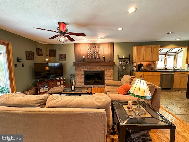 living area featuring ceiling fan, a textured ceiling, stone tile flooring, a fireplace, and recessed lighting