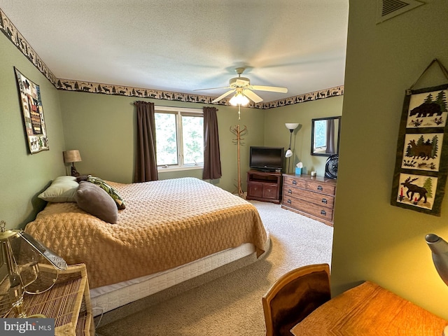 bedroom with a textured ceiling, carpet floors, visible vents, and a ceiling fan