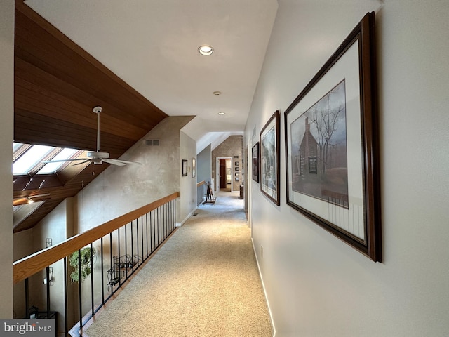 corridor featuring carpet, recessed lighting, visible vents, lofted ceiling with skylight, and baseboards