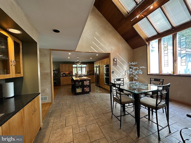 dining room featuring a skylight, stone tile floors, visible vents, baseboards, and recessed lighting