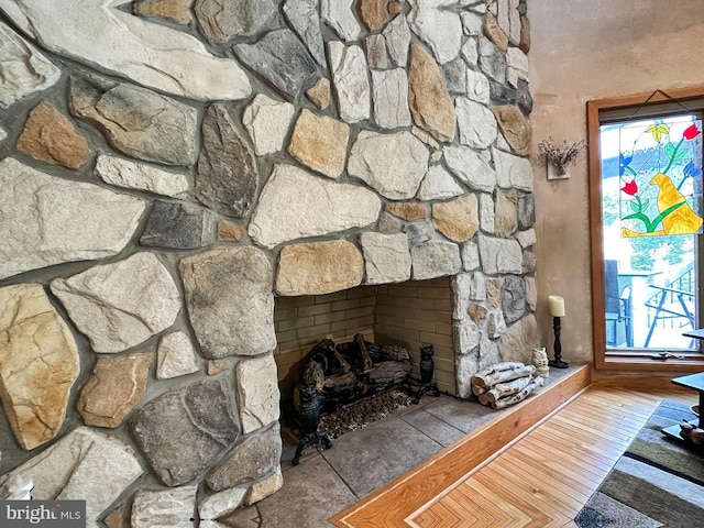 interior details featuring a stone fireplace and wood finished floors