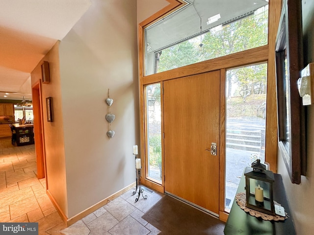 foyer with baseboards, a wealth of natural light, and stone tile floors