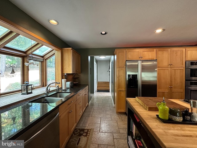 kitchen with stainless steel refrigerator with ice dispenser, stone tile floors, wooden counters, a sink, and dishwasher