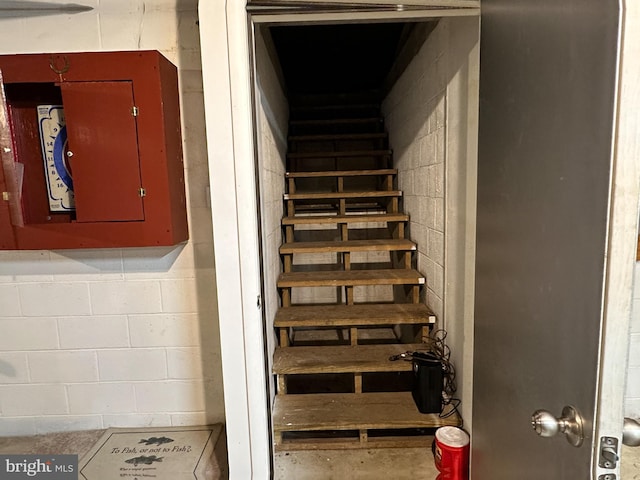 staircase featuring concrete block wall