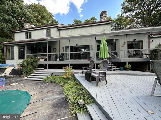 rear view of house featuring stairway, a chimney, and a wooden deck