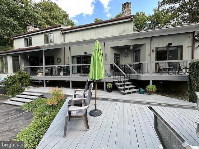 rear view of property featuring a deck and a chimney