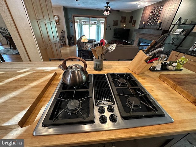 kitchen featuring a brick fireplace, wooden counters, stovetop with downdraft, and open floor plan