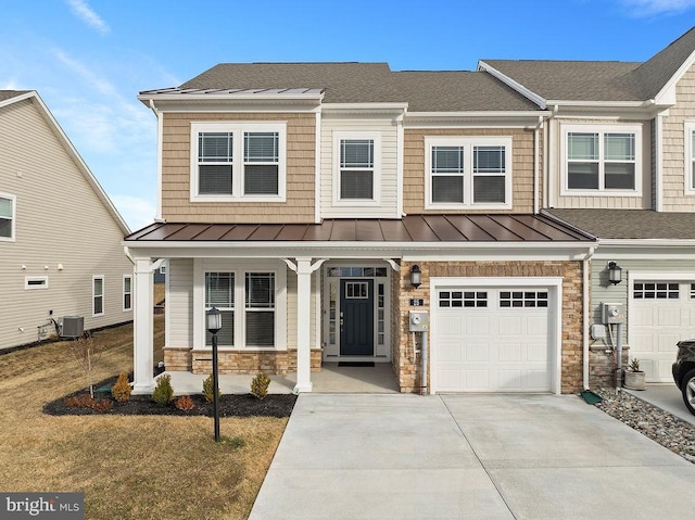 townhome / multi-family property featuring metal roof, covered porch, stone siding, concrete driveway, and a standing seam roof