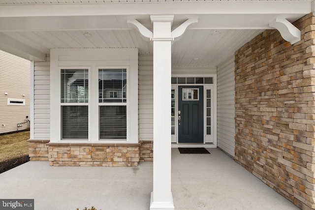 doorway to property featuring stone siding and a porch