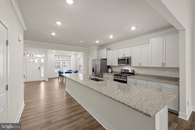 kitchen featuring appliances with stainless steel finishes, ornamental molding, a large island with sink, white cabinetry, and a sink