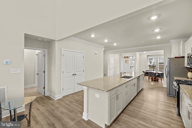 kitchen featuring white cabinets, light wood finished floors, a center island with sink, and stainless steel appliances