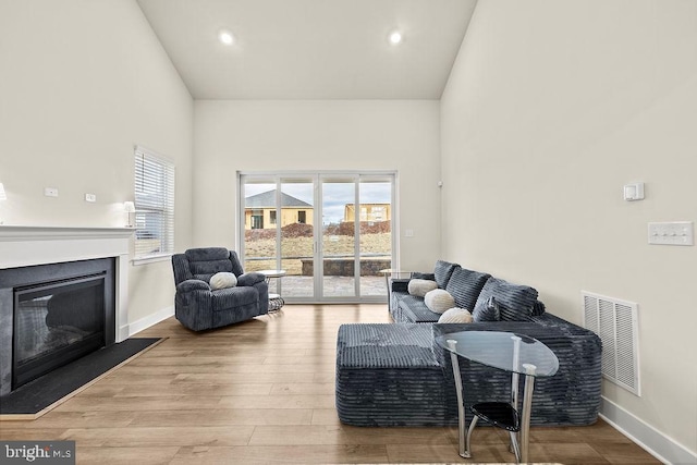 living area featuring wood finished floors, plenty of natural light, a glass covered fireplace, and visible vents