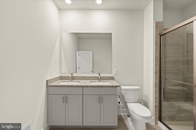 full bath with a sink, a shower stall, toilet, and double vanity