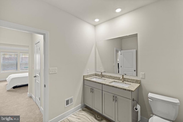 bathroom with visible vents, a sink, toilet, and double vanity