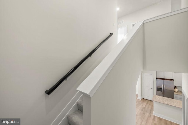 stairs with wood finished floors, visible vents, and baseboards