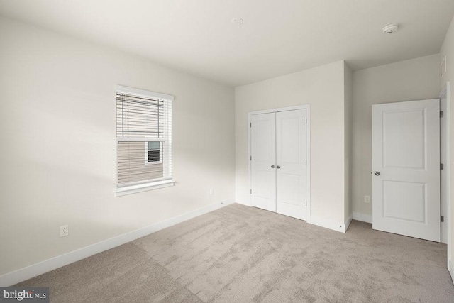 unfurnished bedroom featuring carpet floors, a closet, and baseboards