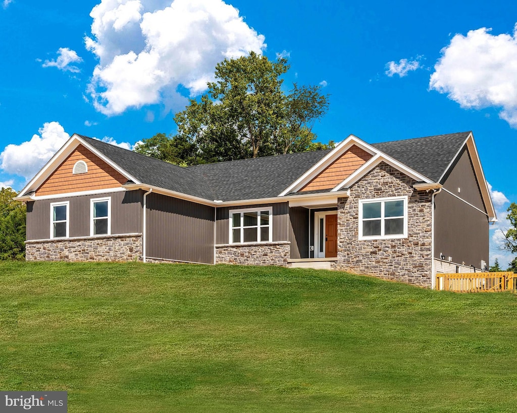 craftsman house with stone siding, roof with shingles, and a front yard