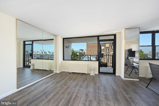 interior space featuring radiator, a view of city, baseboards, and wood finished floors