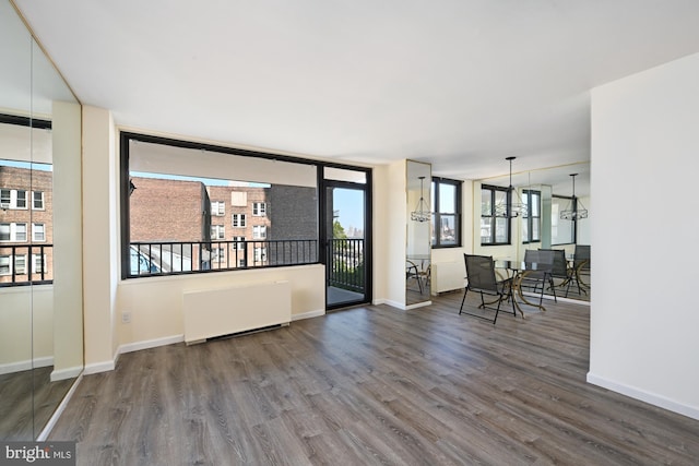 spare room featuring baseboards, radiator heating unit, and wood finished floors