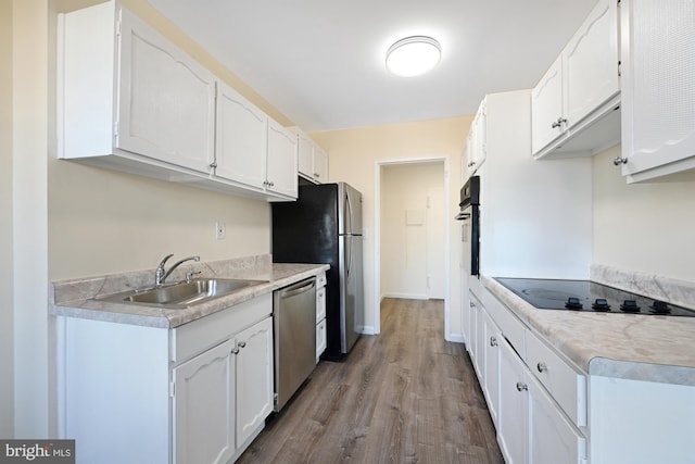 kitchen featuring stainless steel appliances, light countertops, white cabinetry, and a sink