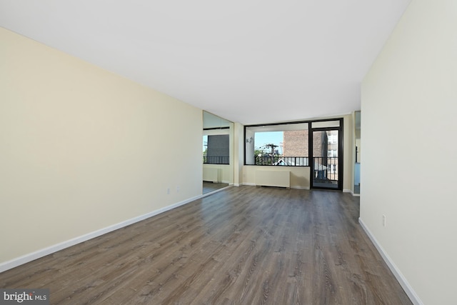 unfurnished living room with baseboards and dark wood finished floors