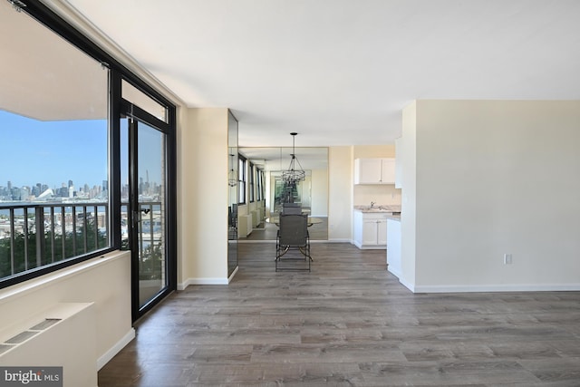 interior space with a view of city, plenty of natural light, wood finished floors, and baseboards