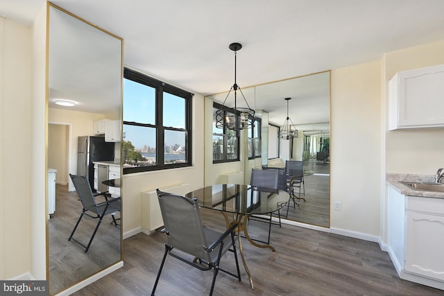 dining room featuring a chandelier, dark wood finished floors, and baseboards