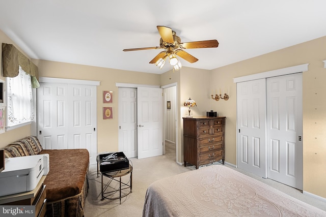 bedroom with baseboards, a ceiling fan, multiple closets, and light carpet