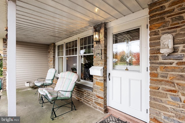 entrance to property featuring covered porch and stone siding