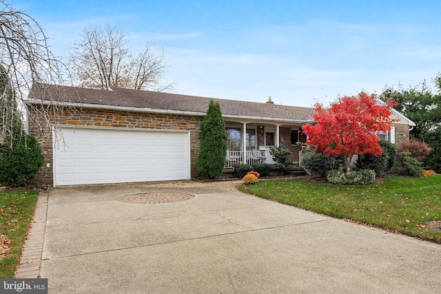 ranch-style house featuring a front yard, covered porch, concrete driveway, a garage, and brick siding