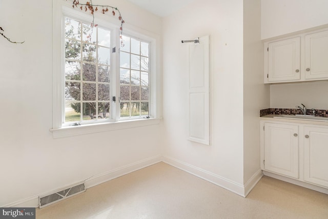 unfurnished dining area featuring a sink, visible vents, plenty of natural light, and baseboards