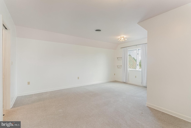 spare room featuring baseboards, light carpet, and visible vents