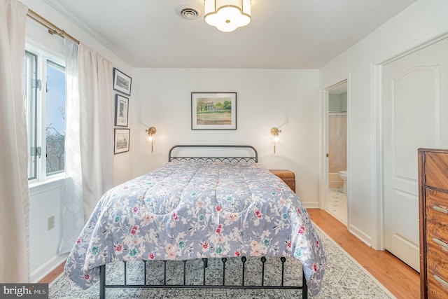 bedroom featuring visible vents, baseboards, light wood-style floors, and a notable chandelier